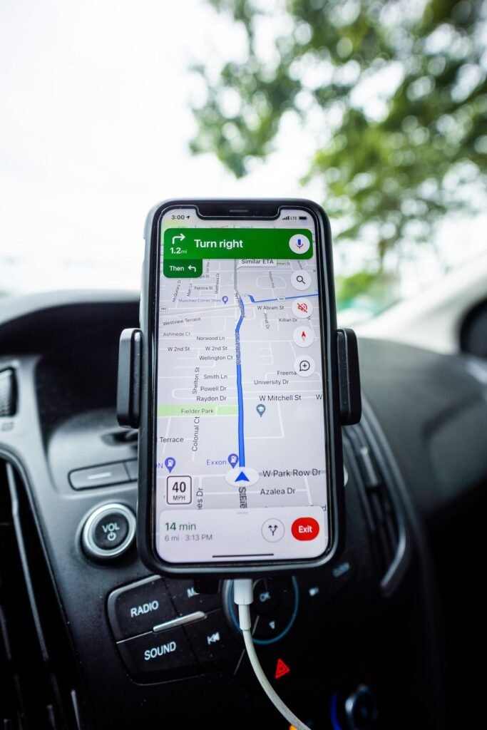 A smartphone mounted on a car dashboard showing Google Maps turn-by-turn navigation directions
