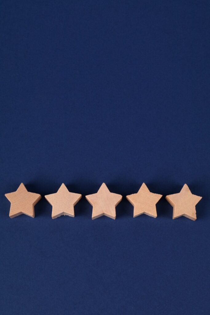 Five wooden star-shaped tokens arranged in a row on a navy blue background, representing a star rating