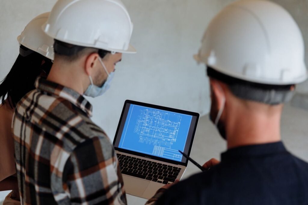 Construction industry professionals in Singapore reviewing a blueprint on a laptop for seo for construction singapore