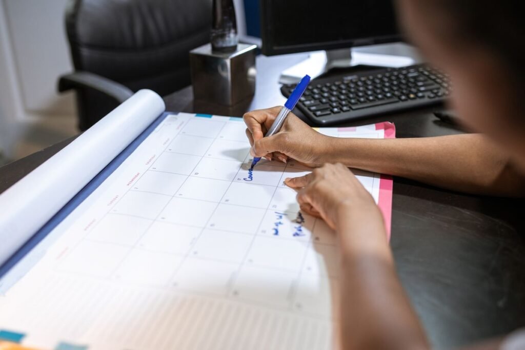 Person writing on a desk calendar representing the seo timeline construction singapore firms should expect