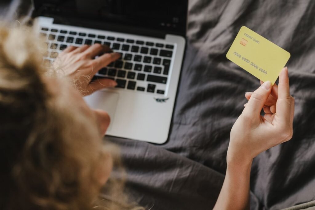 A hand holding a payment card beside a laptop, illustrating the decision to buy guest posts
