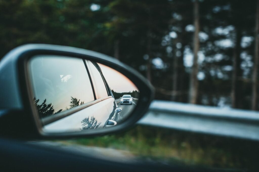 Car side mirror reflecting a road, representing auto insurance marketing around car ownership moments