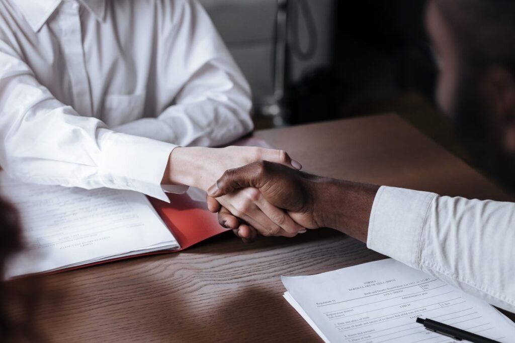 Two professionals shaking hands over a contract, agreeing the scope of a backlink service