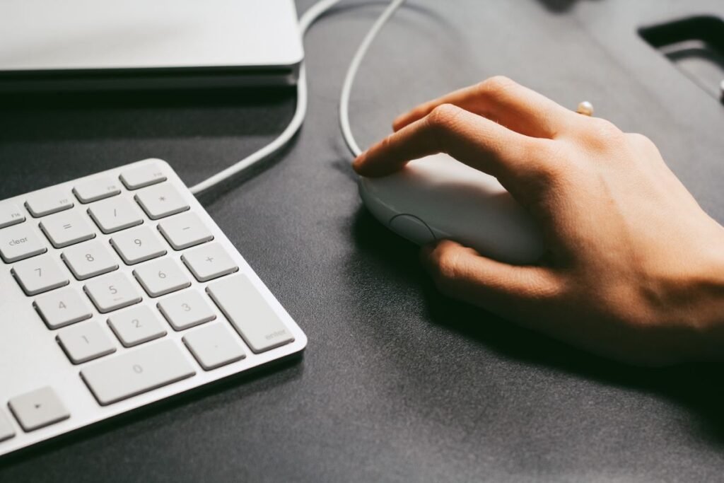 Hand clicking a computer mouse beside a keyboard, the action behind every click through rate