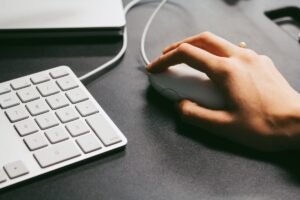Hand clicking a computer mouse beside a keyboard, the action behind every click through rate
