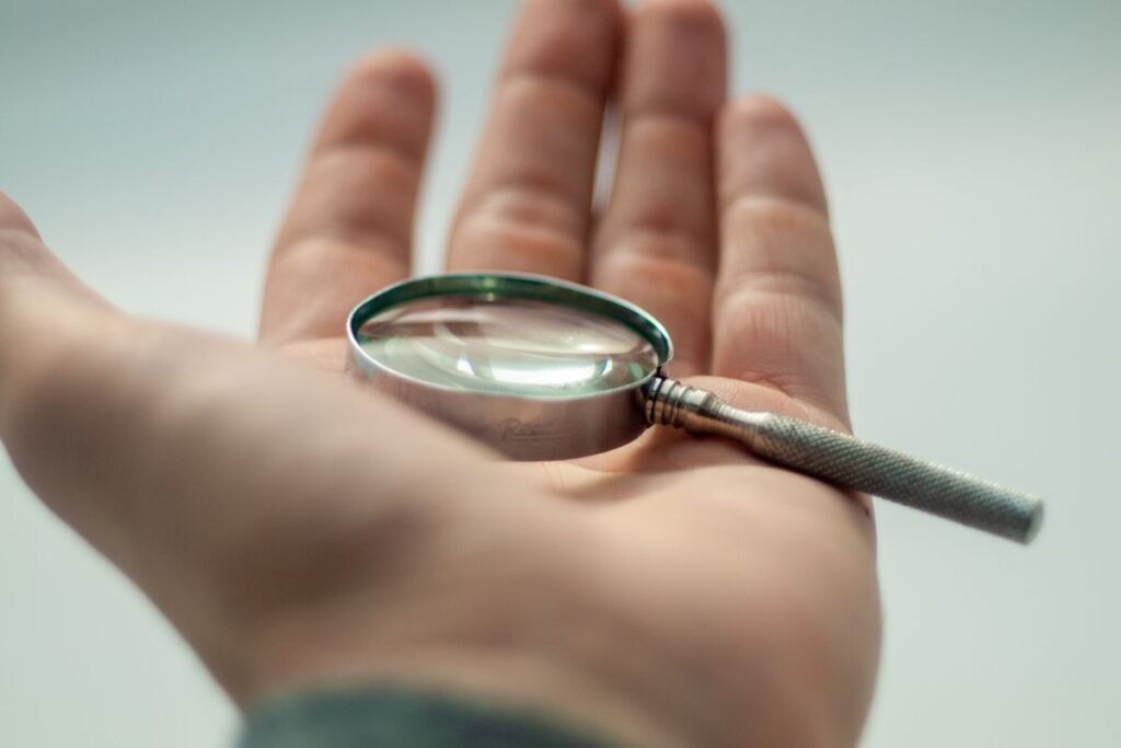 Hand holding a magnifying glass, representing inspection of high quality backlinks