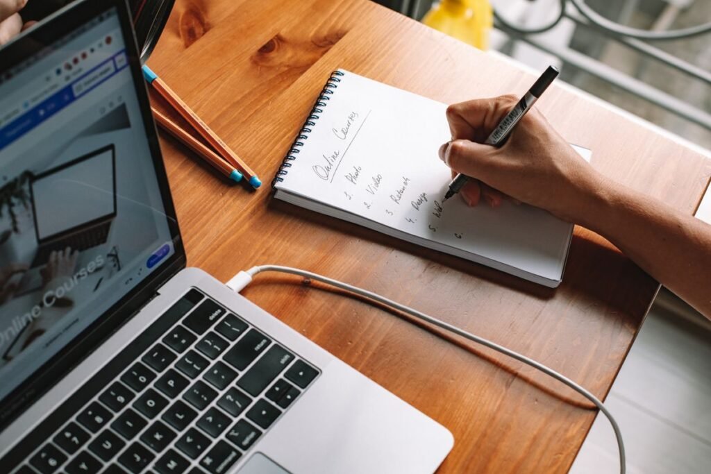 Learner taking notes beside a laptop during an SEO course Singapore professionals can join