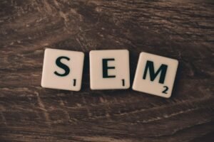 Letter tiles spelling SEM on a wooden table, representing the SEO vs SEM question